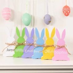 colorful easter bunnies tied with twine in front of a white wall and hanging eggs