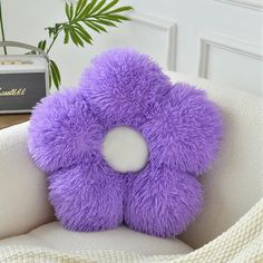 a purple teddy bear sitting on top of a white chair next to a radio and plant