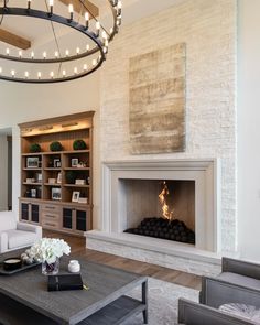 a living room filled with furniture and a fire place under a chandelier over a fireplace