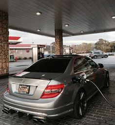 a silver car is parked in front of a gas station with nozzles on it