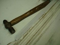 an old hammer is laying on the floor next to a piece of wood