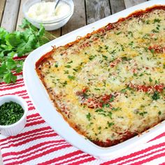 a casserole dish with cheese and vegetables on a red and white tablecloth