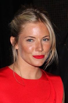 a woman in a red dress is smiling at the camera with her hair pulled back