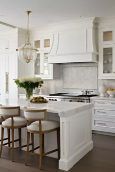 a kitchen with white cabinets and an island in the middle, surrounded by stools