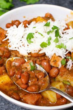 a bowl filled with beans and rice on top of a table next to a spoon