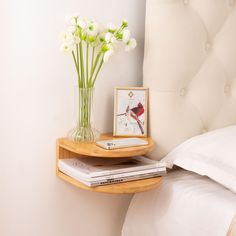 there is a vase with white flowers on the shelf next to books and a bed