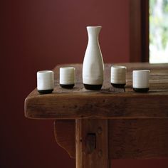 a white vase sitting on top of a wooden table next to four small tea lights