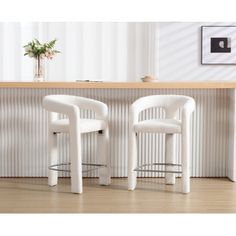 two white chairs sitting next to each other in front of a table with a potted plant