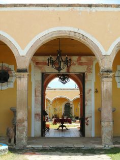 an archway leading into a courtyard with chandelier hanging from it's ceiling