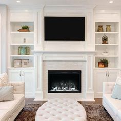 a living room with white furniture and a flat screen tv mounted above the fire place