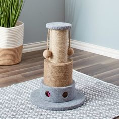 a cat scratching tower on top of a rug next to a potted green plant