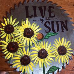 sunflowers painted on a metal plate with the words live by the sun above them