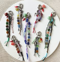 a white plate topped with lots of different types of beads and keychain charms