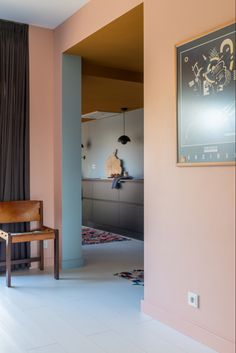 an open door leading to a living room with pink walls and white tile flooring