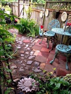 an outdoor patio with blue chairs and table in the middle of it, surrounded by greenery