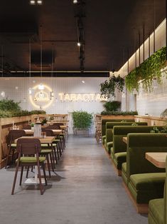 an empty restaurant with green chairs and plants