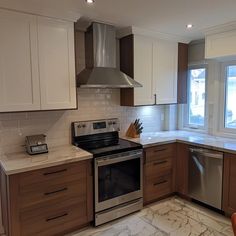 an empty kitchen with stainless steel appliances and marble counter tops in front of a large window