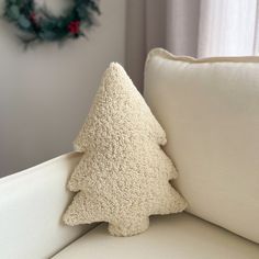 a christmas tree pillow sitting on top of a couch next to a white throw pillow