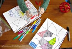 the child is drawing on paper with colored pencils