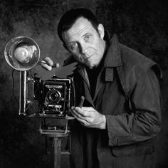 a man holding an old fashioned camera in front of his face