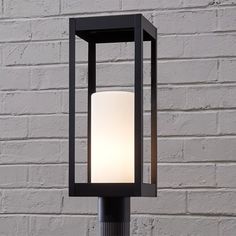 a lamp on a post in front of a brick wall with a white light inside