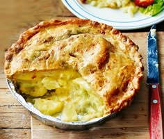 a pie sitting on top of a wooden table next to a knife