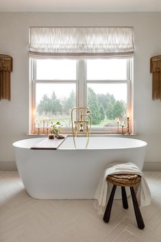 a white bath tub sitting under a window next to a stool and windowsills