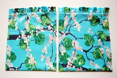 two pieces of blue fabric with pink flowers and green leaves on them, sitting next to each other