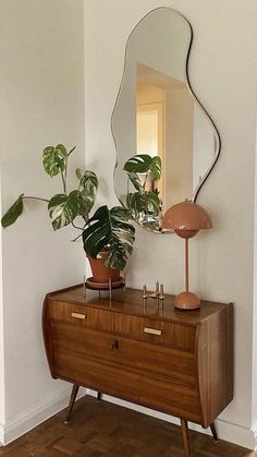 a mirror and some plants on a dresser in a room with blue walls, wood floors and wooden flooring