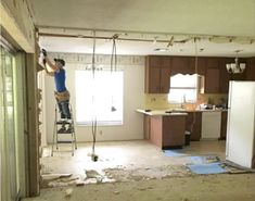 a man standing on a ladder in an unfinished kitchen