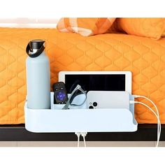 a bed with an orange bedspread and a white shelf holding items on it