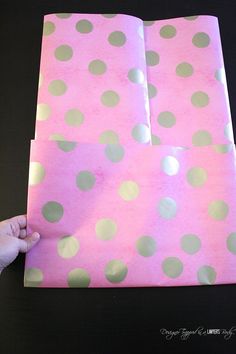 a hand is holding some pink and green polka dot paper