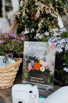 there is a sign that says polaroid your photos on the table next to some flowers