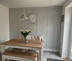 a kitchen table with two benches and a clock on the wall