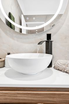 a white bowl sink sitting under a round mirror