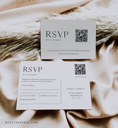 two white business cards sitting on top of a bed next to a fur covered blanket