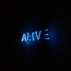 the word alive is lit up in the dark with blue light coming from behind it