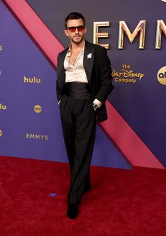 a man in a tuxedo and sunglasses on the red carpet at an event