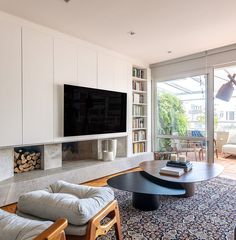 a living room filled with furniture and a flat screen tv mounted on the wall above a fireplace