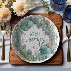 a christmas plate with the words merry christmas on it next to silverware and flowers