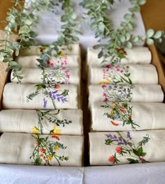 napkins with flowers and greenery on them are arranged in a box for display