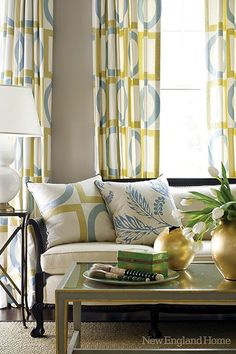 a living room filled with furniture next to a window covered in yellow and green curtains