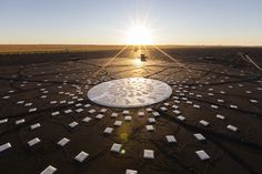 the sun shines brightly over an array of solar panels on top of a field