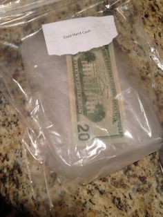 a $ 20 bill wrapped in plastic sitting on top of a marble countertop next to a knife