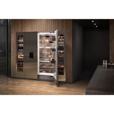 an open refrigerator in a kitchen with wooden walls and flooring, along with shelves filled with food