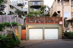 two garages are on the side of a street in front of apartment buildings with balconies