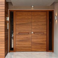 a large wooden door in the middle of a room with white tile flooring and walls