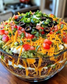 a large bowl filled with taco salad on top of a wooden table