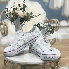 pair of white sneakers with flowers on table in room