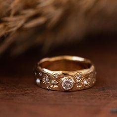 a close up of a gold ring with three diamonds on the inside and outside, sitting on a wooden surface